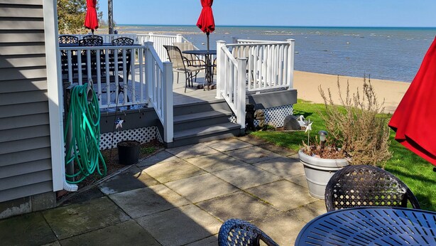 A deck with outdoor furniture and a view of the beach. - Beachfront home cure for high blood pressure (Harbor Beach)