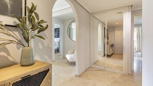 Un intérieur moderne avec une console en bois, une grande plante, un miroir et une chaise blanche.