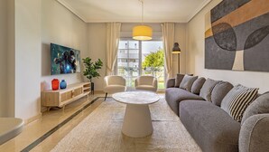 Un salon moderne avec un canapé, des fauteuils, une table basse et un tableau accroché au mur.