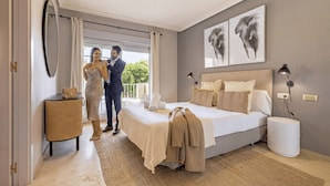 Une chambre avec un grand lit, une lampe de chevet et une vue sur l’extérieur.