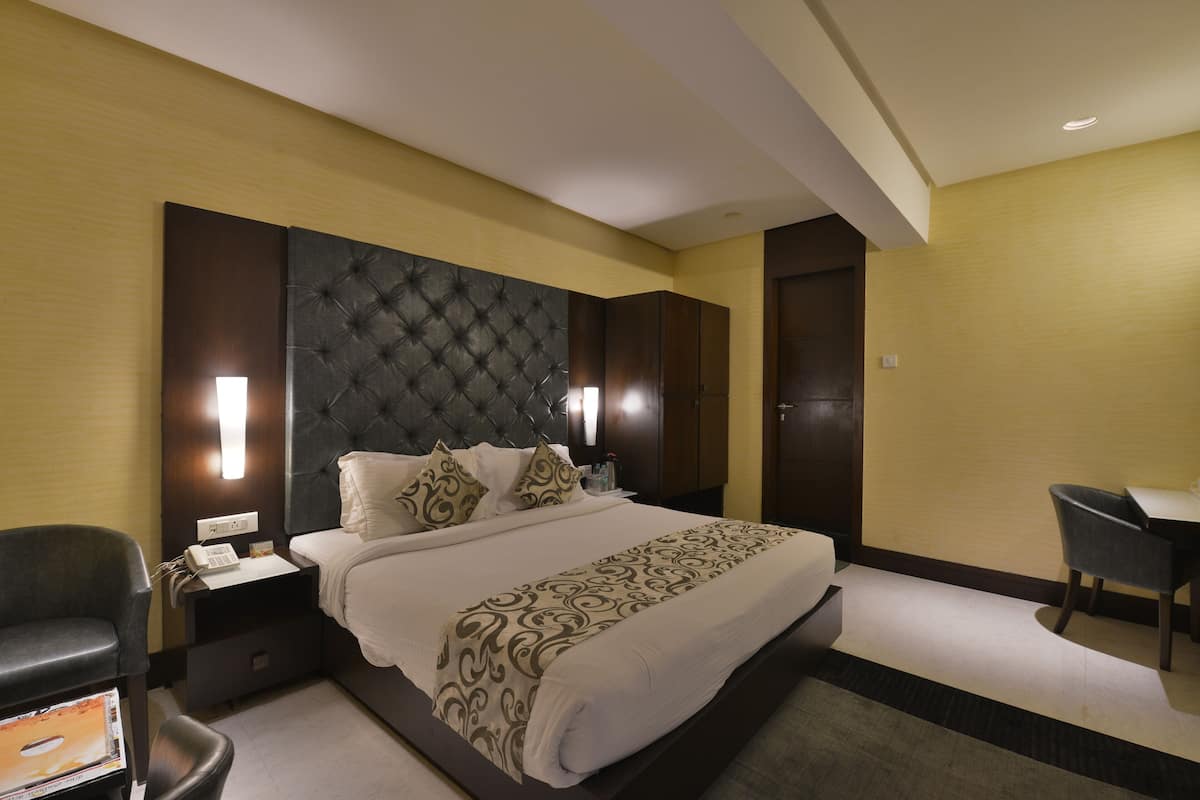 A hotel room with a large bed, a desk, and a chair.