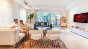 A modern living room with a sofa, two armchairs, a coffee table, and a TV mounted on the wall.