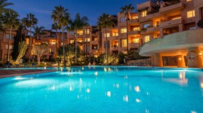 A hotel with a swimming pool, palm trees, and multiple balconies. - 4-BEDROOM LOVELY FLAT IN TOP LOCATED CONDO WITH SAUNA, GYM & PLAYGROUND (Marbella)