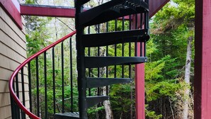 A spiral staircase with a red handrail leading to a covered outdoor area. - Newly built quiet studio apartment near Reversing Falls (Blue Hill)