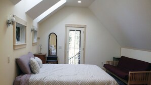 A bedroom with a bed, a dresser, a mirror, a window, and a door leading to a balcony. - Newly built quiet studio apartment near Reversing Falls (Blue Hill)