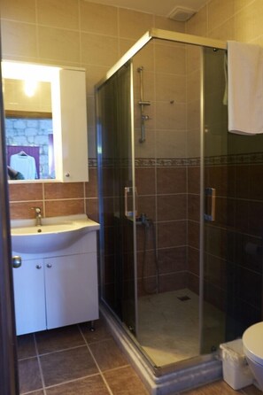 A bathroom with a glass-enclosed shower, a white sink, and a mirror above it. - Sila Alacati (Cesme)