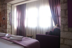 A hotel room with a bed, a small round table, and a purple armchair. - Sila Alacati (Cesme)