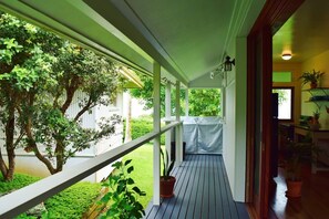 A covered porch with a view of a garden and a house. - Ohia Hale, Hawi, North Kohala (Hawi)