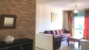 Una sala de estar con pared de ladrillo, un sofá, una mesa y una araña.