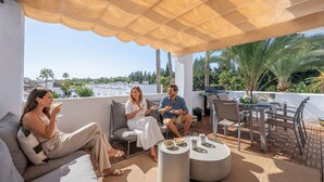 Une terrasse sur le toit, dotée d’un espace salon couvert, d’un barbecue et offrant une vue sur le paysage urbain.