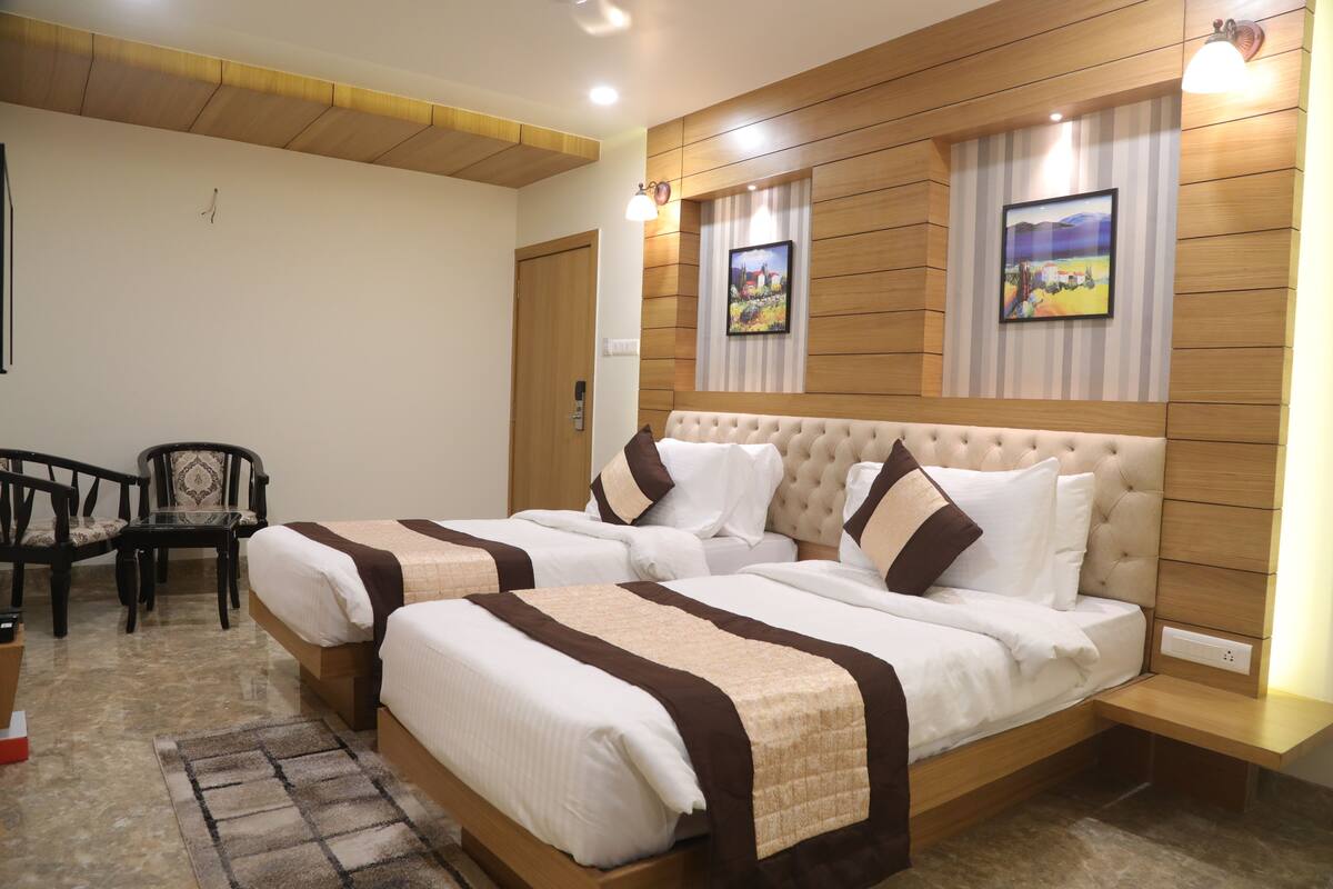 Une chambre d’hôtel avec deux lits, une tête de lit en bois, une petite table, une chaise et un tapis.