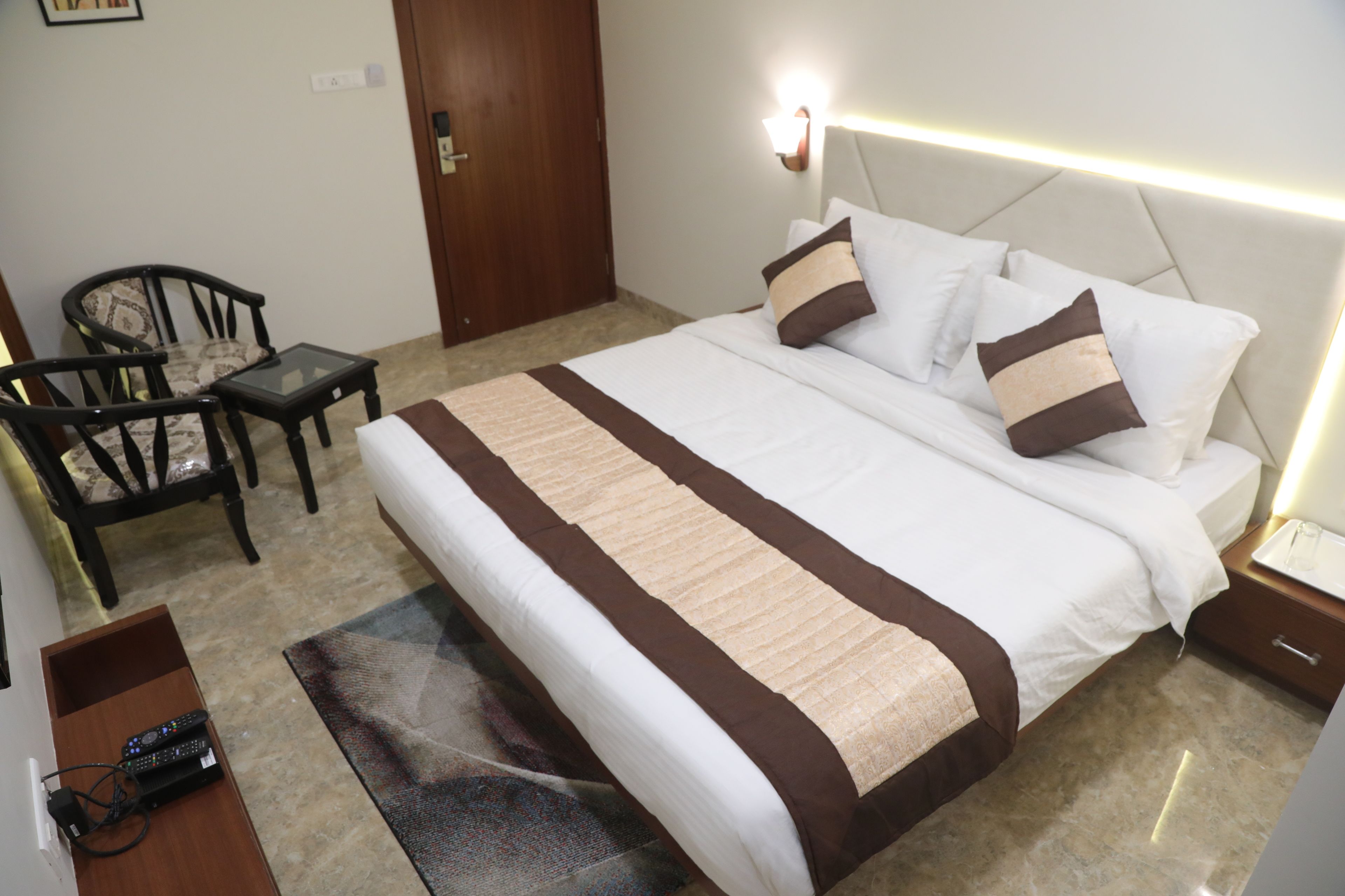 A hotel room with a bed, a nightstand, a chair, and a small table.