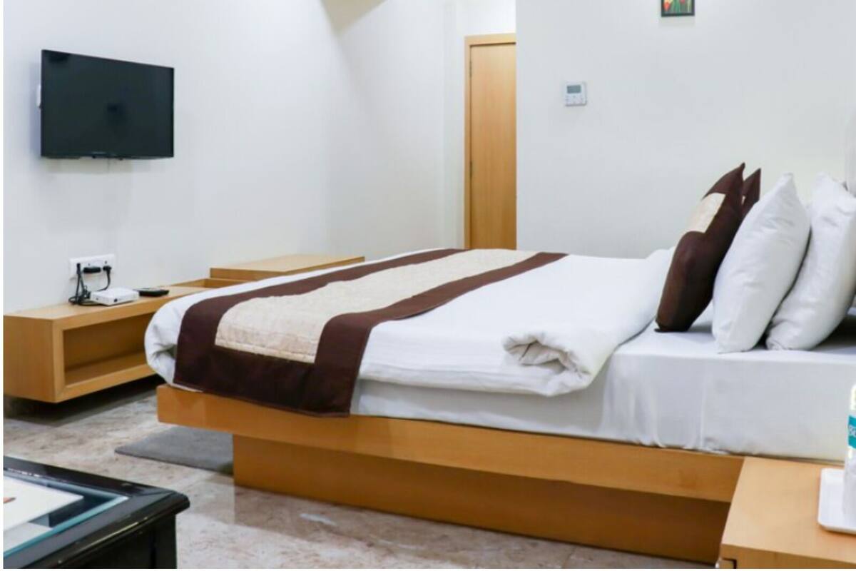 Une chambre d’hôtel moderne équipée d’un lit, d’un téléviseur à écran plat, d’une table de chevet en bois et d’une petite table.