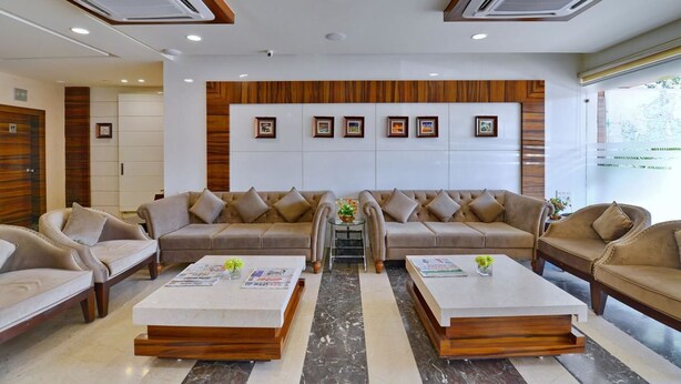 A modern reception area with a sofa, two coffee tables, and framed pictures on the wall. - Hotel Western (Bhopal)
