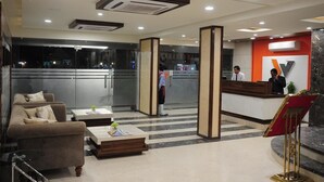A hotel lobby with a reception desk, a sofa, and a coffee table. - Hotel Western (Bhopal)