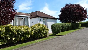 Ein Wohnhaus mit gepflasterter Auffahrt, Rasen und einem gepflegten Heckenstreifen.