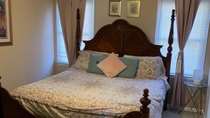 Un dormitorio con cama de madera, ventilador de techo y ventana con cortinas.