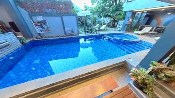 Een buitenzwembad, parasols bij het zwembad en ligstoelen