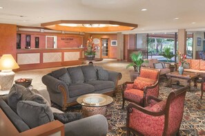 Un hall d’hôtel comprenant un comptoir d’accueil, un espace salon et une vue sur l’extérieur.