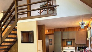 Een gezellige woonkamer met een eethoek, een houten trap en een keuken.