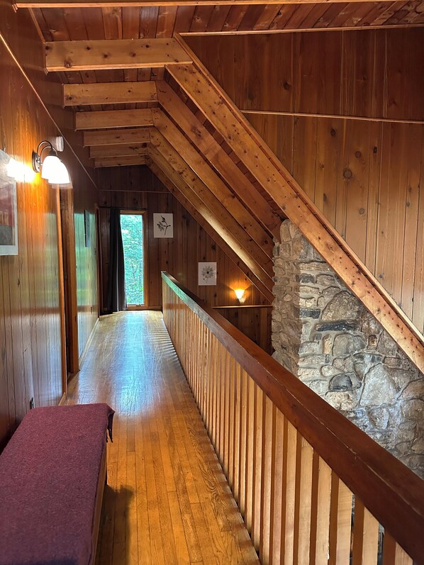 A wooden interior with a sloped ceiling, a stone wall, and a wooden railing along a corridor. - Bedrooms 2, Bathrooms 1.5, Sleeps 4 (Front Royal)