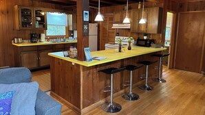 Eine Küche mit Holzausstattung, einer zentralen Kochinsel mit Barhocker, einem Kühlschrank und einem Herd.