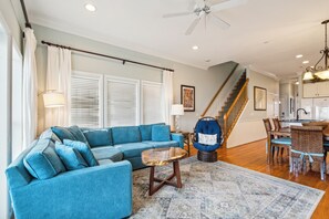 A spacious living room with a blue sofa, a coffee table, and a dining area with chairs and a table.