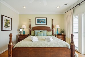 A neatly made bed with a wooden headboard, two bedside tables with lamps, and a framed picture on the wall.
