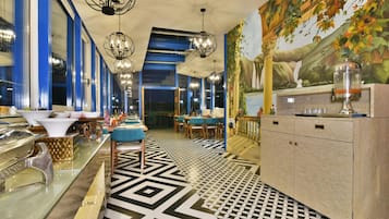 Un restaurante con una decoración moderna, que incluye un piso estampado, detalles azules y blancos, y un mural en la pared.