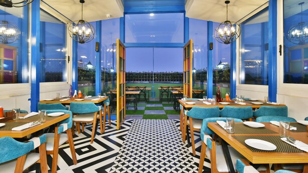 Un restaurante con paredes azules, mesas de madera y sillas color turquesa.