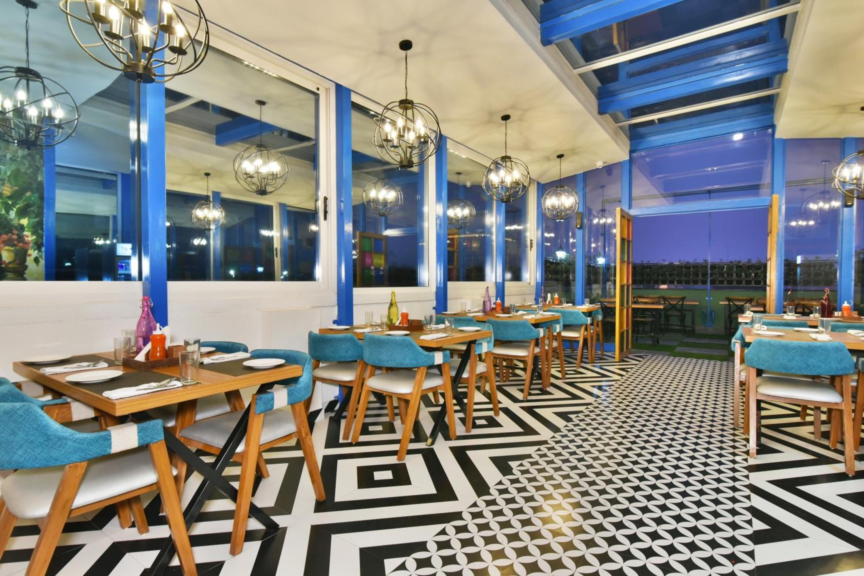 A restaurant with blue chairs, wooden tables, and geometric patterned flooring.
