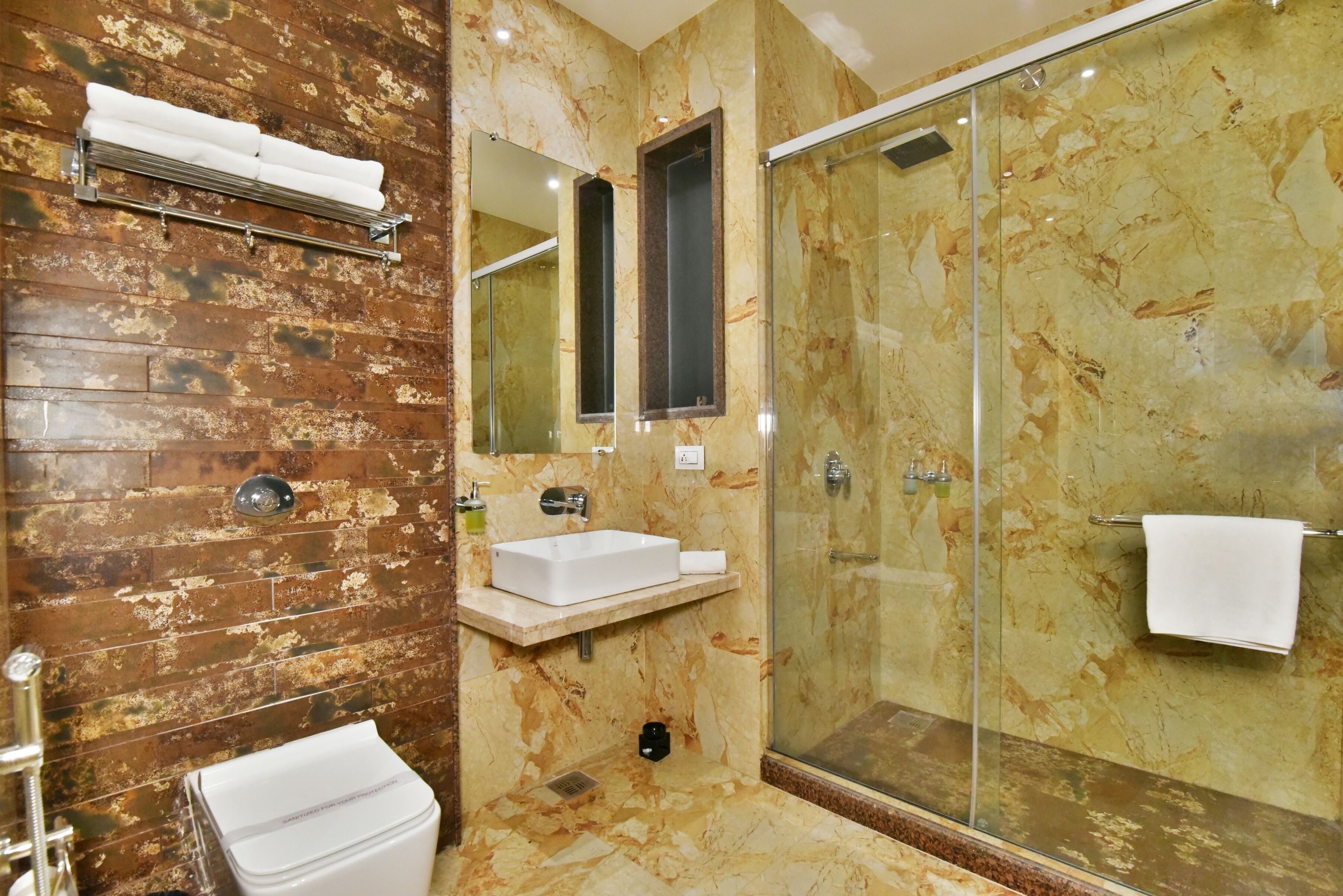 A bathroom with a marble vanity, a glass shower enclosure, and a wooden accent wall.