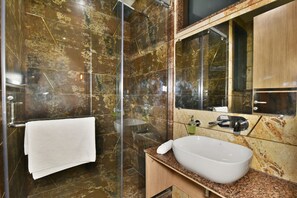 A modern bathroom with a glass-enclosed shower, a white sink, and a large mirror.