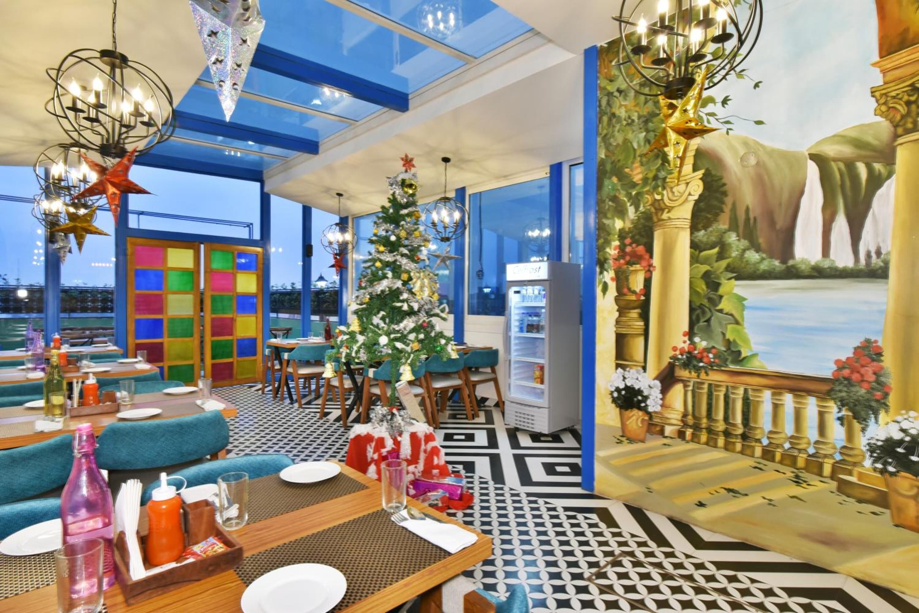 Ein Restaurant mit modernem Interieur, ausgestattet mit einem Weihnachtsbaum, farbenfrohen Wandpaneelen und einem Wandbild einer Wasserfall.