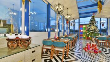 Un restaurante moderno con ventanas amplias, un árbol de Navidad y un diseño de techo singular.