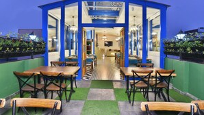Un restaurante con una decoración azul y blanca, que incluye un suelo de cuadros, mesas y sillas de madera, y un pasillo central.