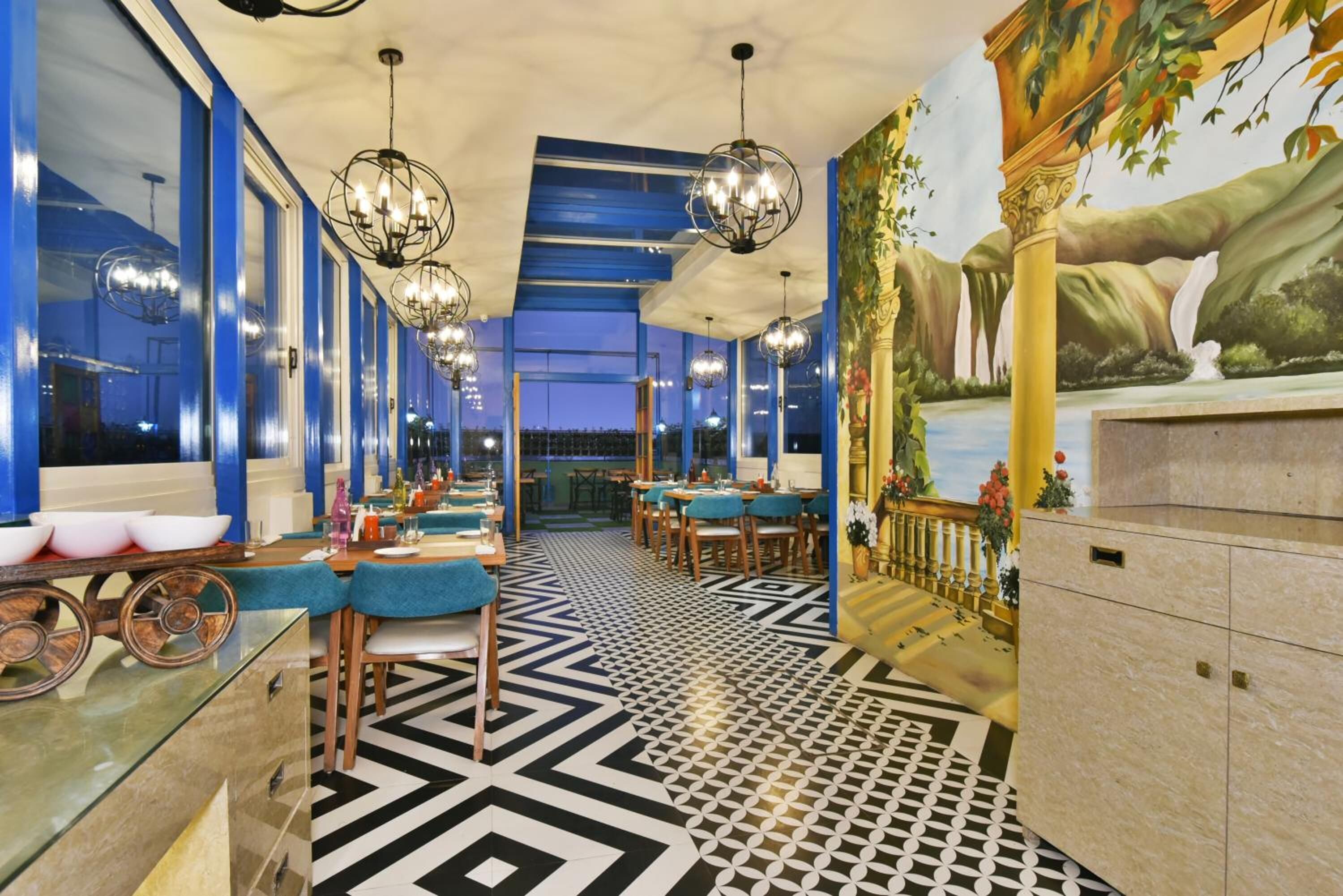 Un restaurante con suelo de estampado geométrico, paredes azules y candelabros.
