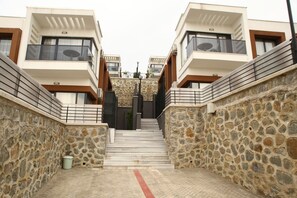A modern building with a stone facade, a central staircase, and balconies on the upper floors.