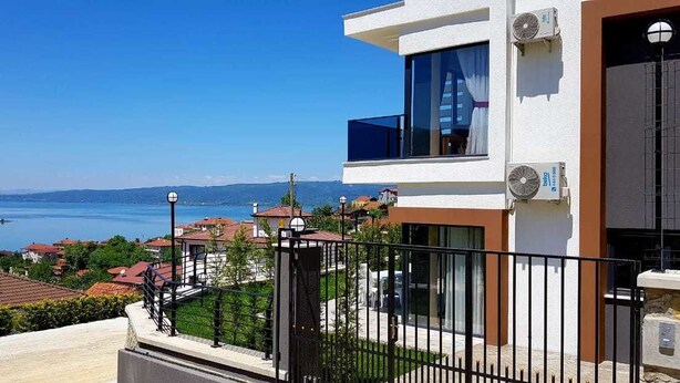 A modern building with a balcony overlooking a body of water and a hilly landscape. - Sawsana Villalari (Sapanca)
