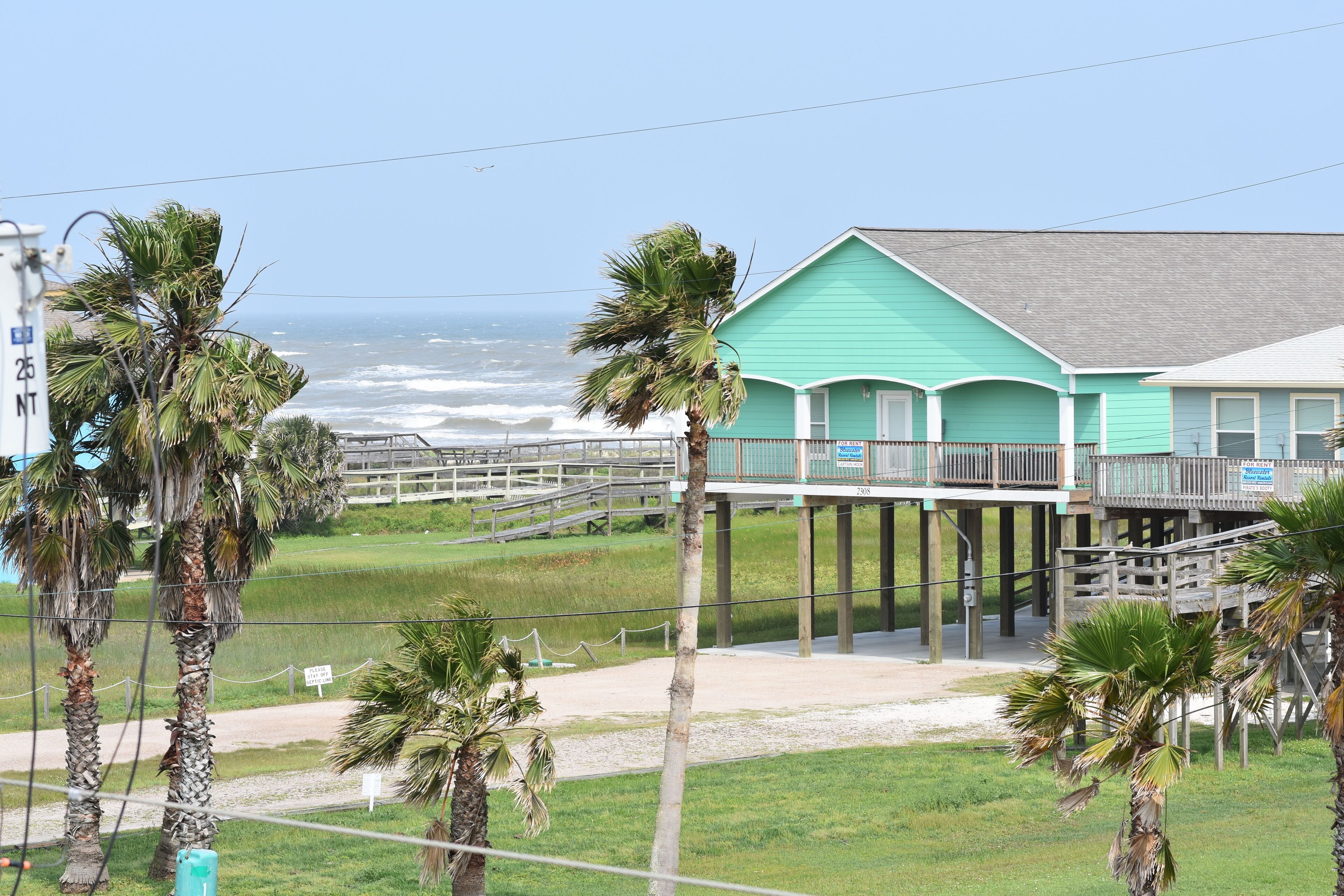 A coastal building with a green facade, wooden deck, and a view of the ocean.