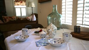 Ein Esstisch mit weißer Tischdecke und blauem Blumengeschirr, darunter Schüsseln, ein Teekessel und Tassen.