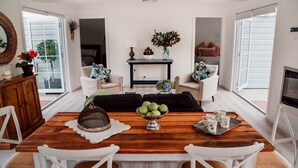 Una sala de estar moderna con una mesa de comedor de madera, sillas blancas, un sofá negro y una chimenea.
