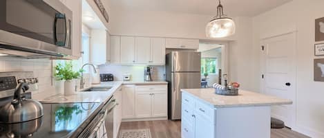 A modern kitchen with white cabinetry, stainless steel appliances, and a central island.