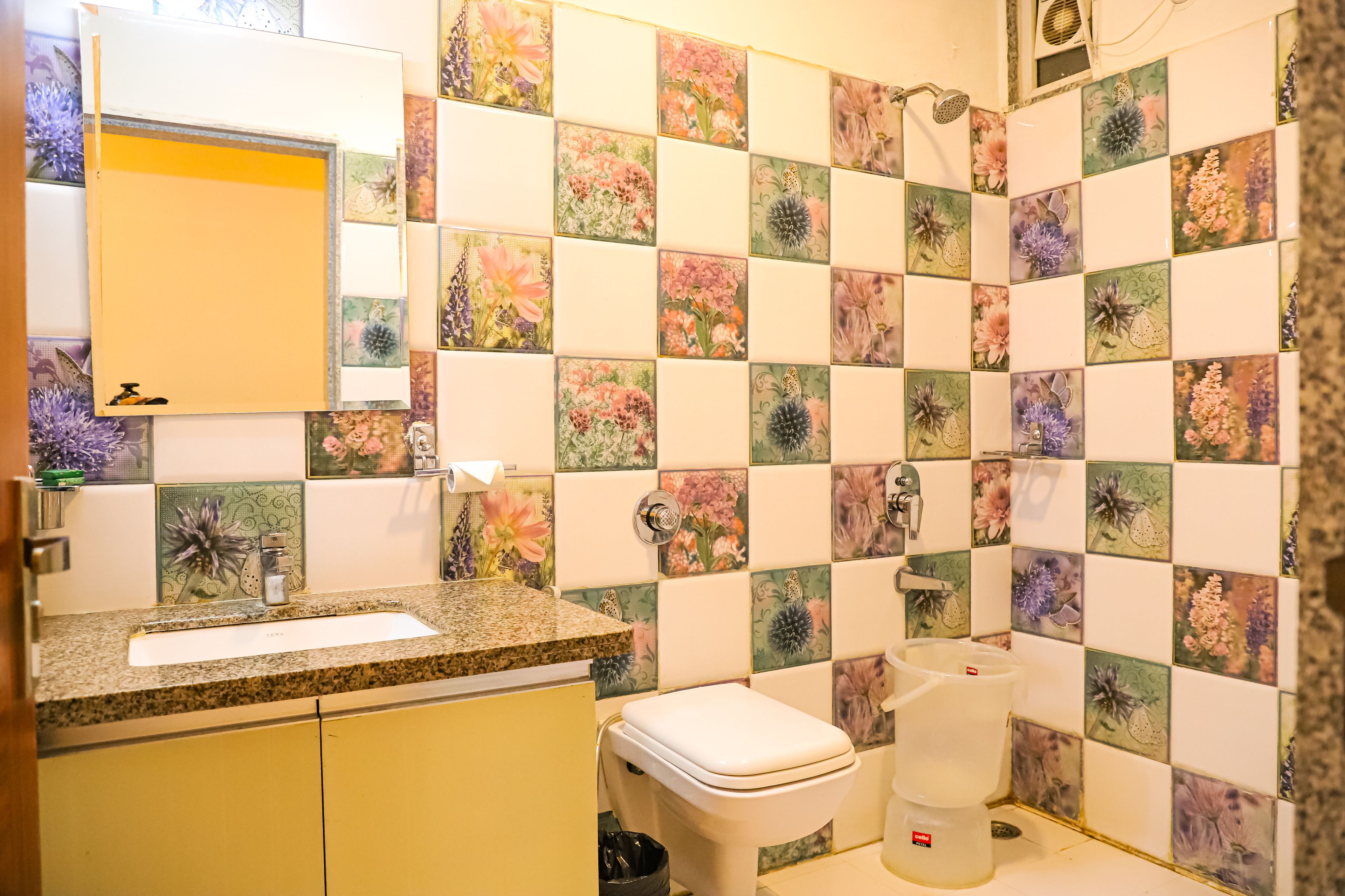 A bathroom with a sink, toilet, and shower. The walls are decorated with floral tiles.