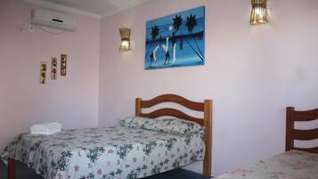 Quarto com uma cama, uma cama menor, um ar condicionado fixado na parede e um quadro.