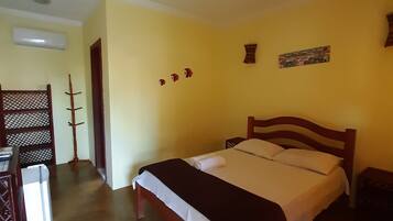 A room with a wooden bed, a desk with a chair, and a wall-mounted air conditioner.