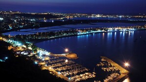 A marina at night with boats docked, a large illuminated structure, and a cityscape in the background. - Meigama, modern loft in historic center of Cagliari (Cagliari)