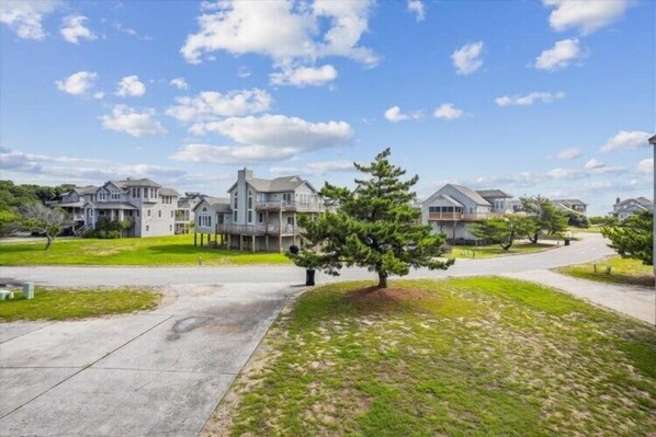 A residential area with houses, a paved driveway, and a grassy lawn.