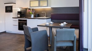 Een moderne keuken met een eethoek, inclusief een tafel met stoelen, een koffiezetapparaat en een waterkoker.
