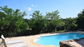 A swimming pool with a curved edge, surrounded by a stone wall and a white lounge chair. - Hillside Villa with Pool, Joyeuse (Joyeuse)